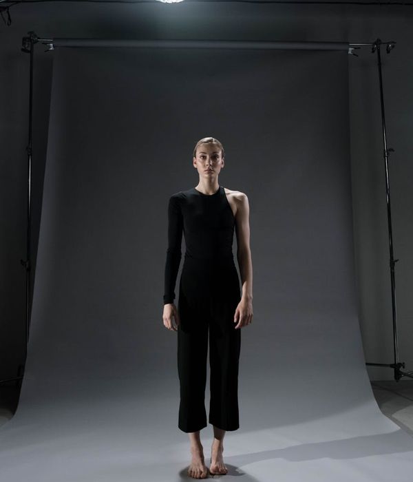 Person in a calm yoga pose in a minimalist dark room.